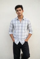 Man wearing a heavy mill-made TFO Oxford windowpane check shirt with double shoulder construction in grey and white, full sleeves rolled at cuffs, black trousers